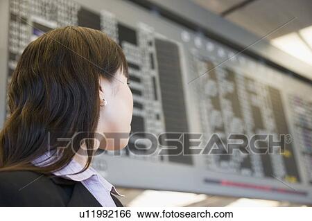 Close-up of a businesswoman at an airport and looking at an arrival departure airport View Large Photo Image Stock Photograph - Close-up of a businesswoman at an airport and looking at an arrival departure airport. Fotosearch