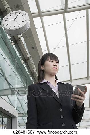 Low angle view of a businesswoman holding a personal data assistant at an airport lounge View Large Photo Image Stock Photo - Low angle view of a businesswoman holding a personal data assistant at an airport lounge. Fotosearch