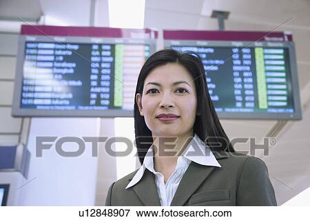 Stock Photo - Portrait of a businesswoman in front of an airport departure board. Fotosearch