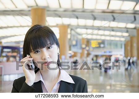 Stock Image - Portrait of a businesswoman talking on a mobile phone at an airport lounge. Fotosearch