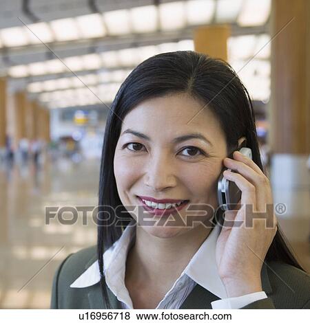 Stock Photo - Portrait of a businesswoman talking on a mobile phone at an airport. Fotosearch