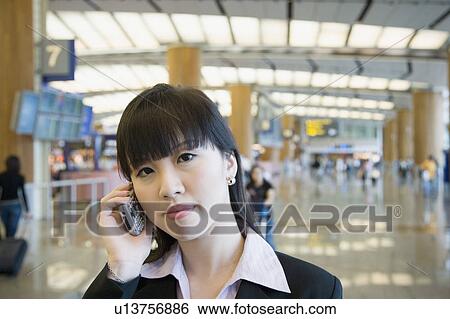 Portrait of a businesswoman talking on a mobile phone at an airport lounge View Large Photo Image Stock Photograph - Portrait of a businesswoman talking on a mobile phone at an airport lounge. Fotosearch