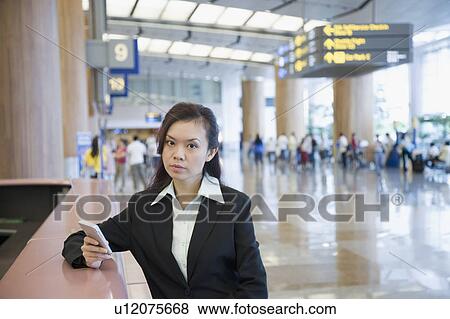 Stock Photo - Portrait of a businesswoman using a hand held device at an airport. Fotosearch