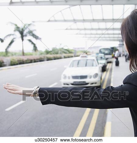 Stock Photo - Rear view of a businesswoman hailing a taxi. Fotosearch