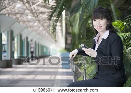 Stock Image - Side profile of a businesswoman and holding a mobile phone. Fotosearch