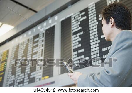 Stock Image - Businessman at an airport holding a mobile phone. Fotosearch