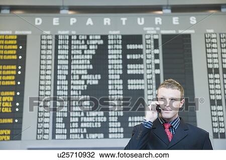 Businessman at an airport talking on a mobile phone View Large Photo Image Stock Image - Businessman at an airport talking on a mobile phone. Fotosearch