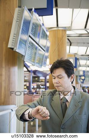 Stock Photo - Businessman checking the time at an airport. Fotosearch