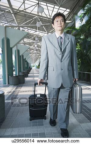 Businessman walking with a luggage and suitcase View Large Photo Image Picture - Businessman walking with a luggage and suitcase. Fotosearch