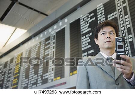 Stock Image - Close-up of a businessman at an airport holding a mobile phone. Fotosearch