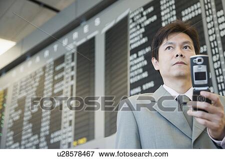 Stock Photo - Close-up of a businessman at an airport holding a mobile phone. Fotosearch