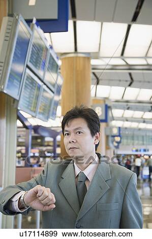 Close-up of a businessman checking the time at an airport View Large Photo Image Stock Photo - Close-up of a businessman checking the time at an airport. Fotosearch