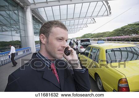 Close-up of a businessman talking on a mobile phone outside an airport View Large Photo Image Stock Image - Close-up of a businessman talking on a mobile phone outside an airport. Fotosearch