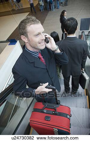 Stock Image - High angle view of a businessman talking on a mobile phone and smiling. Fotosearch