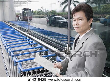 Portrait of a businessman holding a document and waiting outside an airport View Large Photo Image Stock Photo - Portrait of a businessman holding a document and waiting outside an airport. Fotosearch