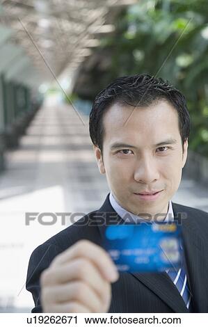 Stock Image - Portrait of a businessman showing a credit card. Fotosearch