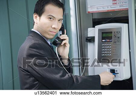 Portrait of a businessman talking on a public phone View Large Photo Image Stock Image - Portrait of a businessman talking on a public phone. Fotosearch