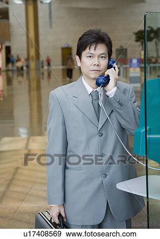 Stock Photo - Portrait of a businessman using a pay phone. Fotosearch