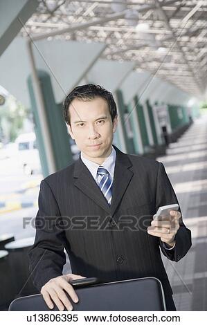 Portrait of a businessman using a palmtop and pushing a luggage cart View Large Photo Image Stock Photography - Portrait of a businessman using a palmtop and pushing a luggage cart. Fotosearch
