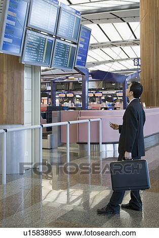 Side profile of a businessman looking at an arrival departure board at an airport View Large Photo Image Stock Photography - Side profile of a businessman looking at an arrival departure board at an airport. Fotosearch
