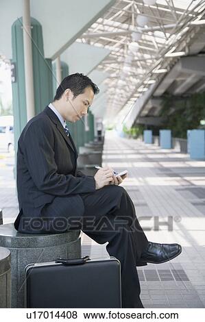 Side profile of a businessman sitting and using a hand held device View Large Photo Image Stock Photo - Side profile of a businessman sitting and using a hand held device. Fotosearch
