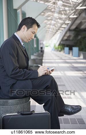 Side profile of a businessman sitting and using a hand held device View Large Photo Image Stock Photography - Side profile of a businessman sitting and using a hand held device. Fotosearch