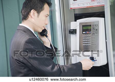 Stock Photograph - Side profile of a businessman talking on a public phone. Fotosearch