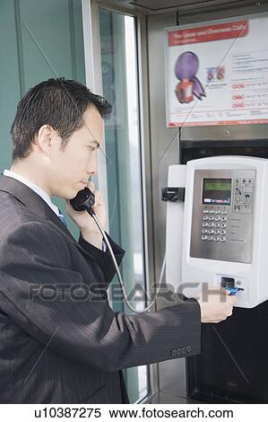 Stock Photography - Side profile of a businessman talking on a public phone. Fotosearch
