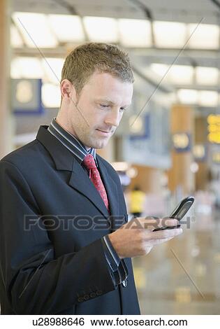Side profile of a businessman using a mobile phone at an airport lounge View Large Photo Image Stock Photograph - Side profile of a businessman using a mobile phone at an airport lounge. Fotosearch