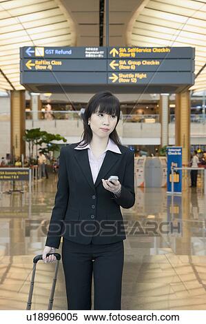Stock Photography - Businesswoman leaving an airport and holding a mobile phone. Fotosearch