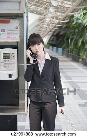 Businesswoman talking on a public phone at an airport View Large Photo Image Stock Photo - Businesswoman talking on a public phone at an airport. Fotosearch