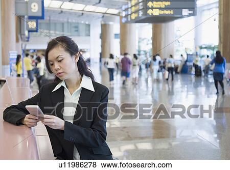 Businesswoman using a hand held device at an airport View Large Photo Image Stock Photo - Businesswoman using a hand held device at an airport. Fotosearch
