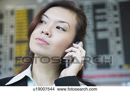 Close-up of a businesswoman at an airport and talking on a mobile phone View Large Photo Image Picture - Close-up of a businesswoman at an airport and talking on a mobile phone. Fotosearch