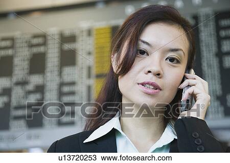 Close-up of a businesswoman at an airport and talking on a mobile phone View Large Photo Image Stock Image - Close-up of a businesswoman at an airport and talking on a mobile phone. Fotosearch
