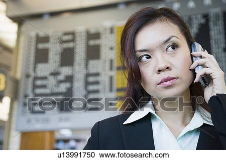 Close-up of a businesswoman at an airport and talking on a mobile phone View Large Photo Image Stock Image - Close-up of a businesswoman at an airport and talking on a mobile phone. Fotosearch