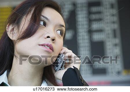Close-up of a businesswoman at an airport and talking on a mobile phone View Large Photo Image Stock Image - Close-up of a businesswoman at an airport and talking on a mobile phone. Fotosearch
