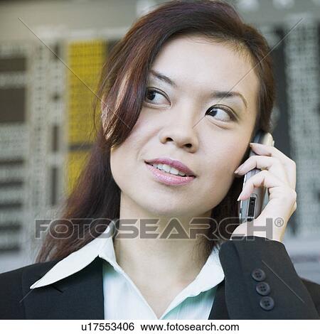 Close-up of a businesswoman at an airport and talking on a mobile phone View Large Photo Image Stock Photograph - Close-up of a businesswoman at an airport and talking on a mobile phone. Fotosearch