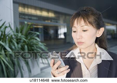 Stock Photo - Close-up of a businesswoman looking at a mobile phone. Fotosearch