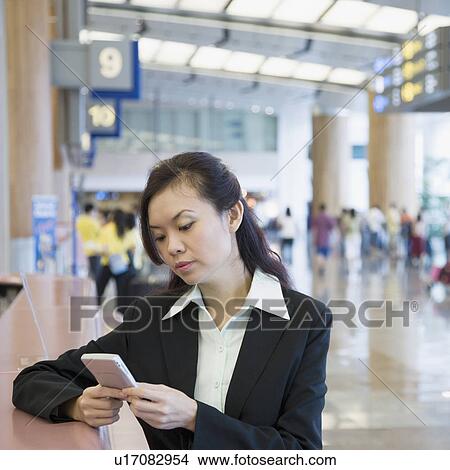 Close-up of a businesswoman using a hand held device at an airport View Large Photo Image Picture - Close-up of a businesswoman using a hand held device at an airport. Fotosearch