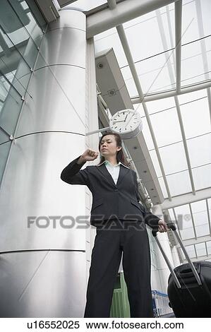 Low angle view of a businesswoman looking at her wristwatch at an airport lounge View Large Photo Image Stock Photography - Low angle view of a businesswoman looking at her wristwatch at an airport lounge. Fotosearch