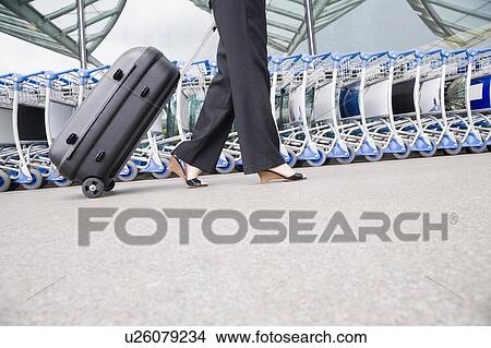 Low section view of a businesswoman pulling luggage outside an airport View Large Photo Image Picture - Low section view of a businesswoman pulling luggage outside an airport. Fotosearch
