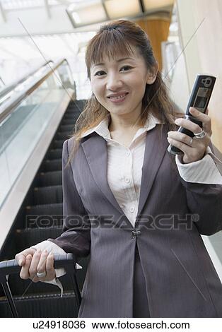 Portrait of a businesswoman holding a mobile phone and a suitcase View Large Photo Image Stock Photograph - Portrait of a businesswoman holding a mobile phone and a suitcase. Fotosearch