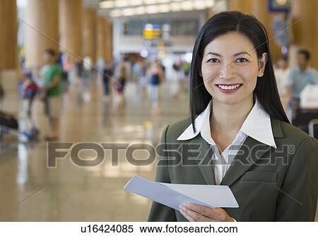 Stock Photography - Portrait of a businesswoman holding an airplane ticket. Fotosearch