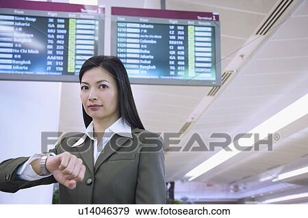 Stock Photo - Portrait of a businesswoman in front of an airport departure board. Fotosearch