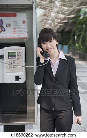 Portrait of a businesswoman talking on a public phone at an airport View Large Photo Image Stock Image - Portrait of a businesswoman talking on a public phone at an airport. Fotosearch