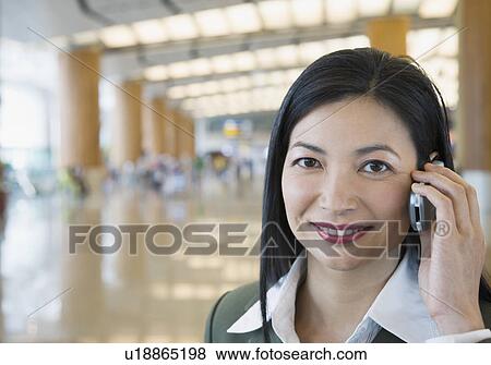 Stock Photo - Portrait of a businesswoman talking on a mobile phone at an airport. Fotosearch