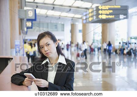 Portrait of a businesswoman using a hand held device at an airport View Large Photo Image Stock Photo - Portrait of a businesswoman using a hand held device at an airport. Fotosearch