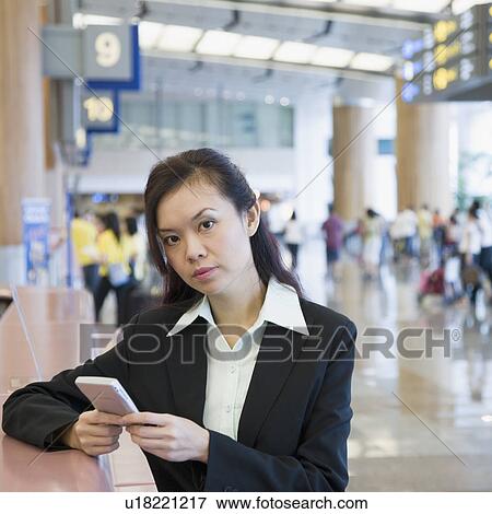 Portrait of a businesswoman using a hand held device at an airport View Large Photo Image Stock Photo - Portrait of a businesswoman using a hand held device at an airport. Fotosearch