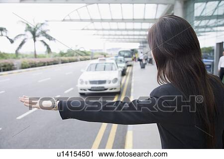 Rear view of a businesswoman hailing a taxi View Large Photo Image Stock Image - Rear view of a businesswoman hailing a taxi. Fotosearch