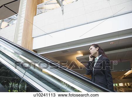 Stock Image - Side profile of a businesswoman talking on a mobile phone. Fotosearch